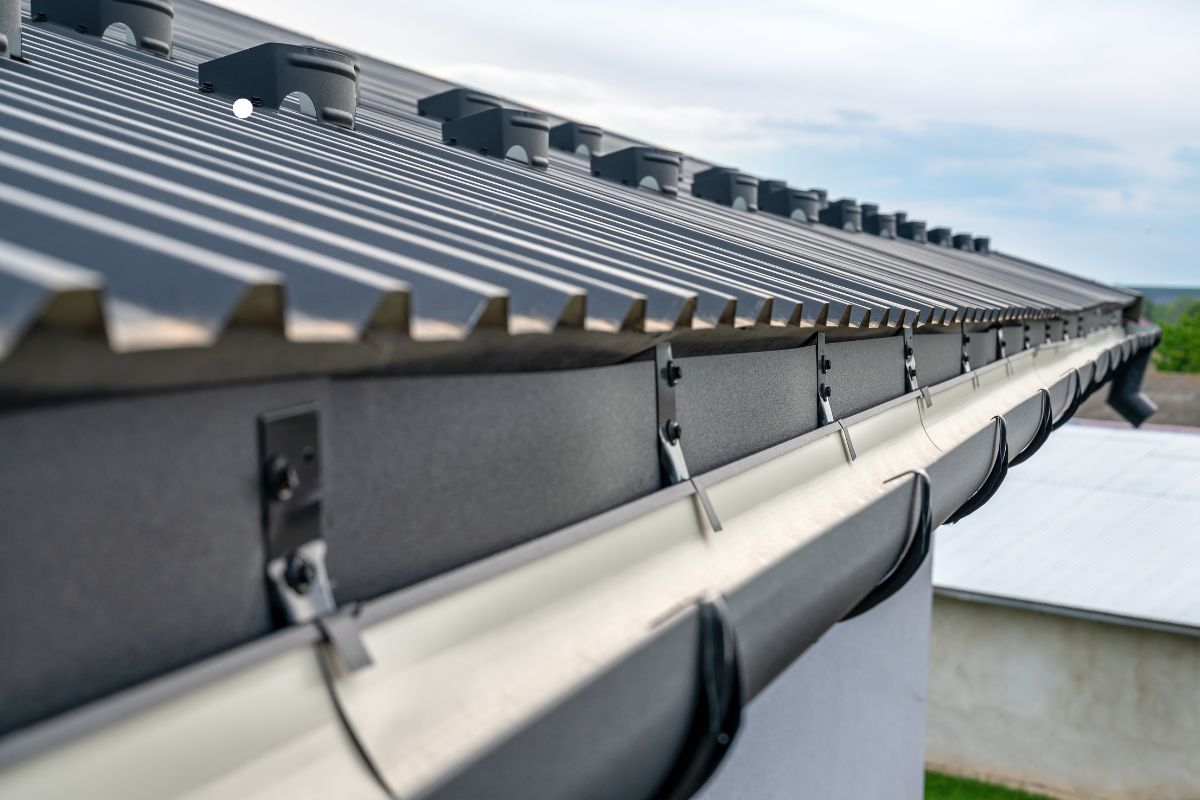 Close-up view of a metal roof gutter, showcasing its design and functionality for roofing services