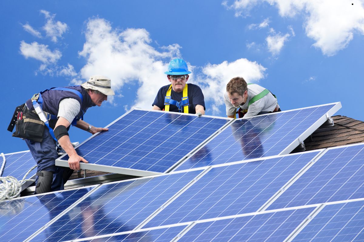  Three men installing solar panels on a roof, showcasing professional roofing services in action